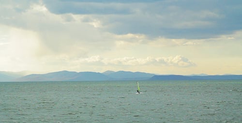 Windsurfer Sailing on Choppy Waters with Mountain Backdrop