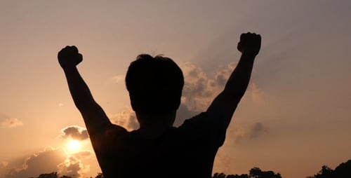 Silhouette Raises Arms in Colorful Sunset