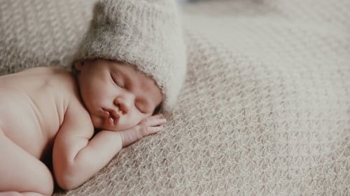 Infant Sleeps Peacefully Wearing Knit Cap on Blanket