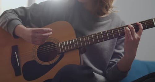Young Woman Plays Acoustic Guitar Indoors