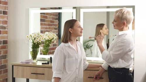 Makeup Artist Applying Cosmetics to a Young Woman