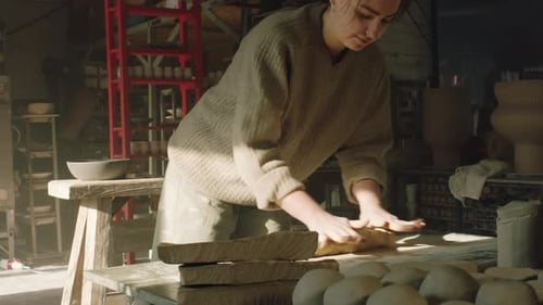 Young Woman Working with Clay in Sunlit Pottery Studio