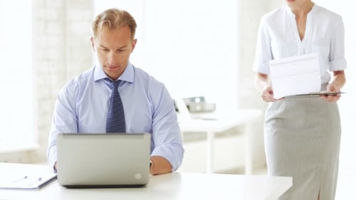 Businessman With Laptop Signing Papers At Office