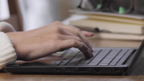 Hands Typing on Laptop Keyboard in Workplace