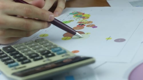 Man Analyzing Charts and Using Calculator