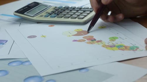 Analyzing Data with Calculator and Pen in Workplace