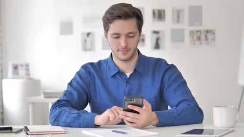 Man Using Smartphone at Desk in Office