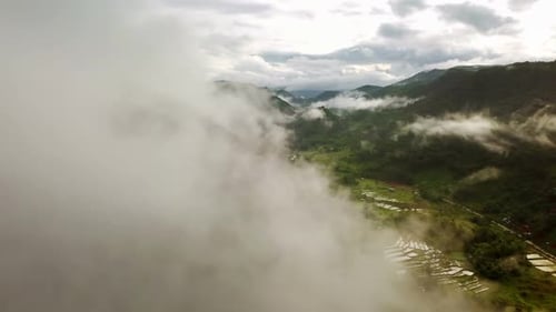 Aerial view flying above lush green tropical rain forest mountain with rain cloud cover during the r