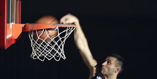 Basketball Player Dunks the Ball Through the Hoop