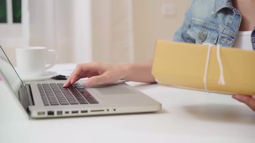 Woman Typing with Package on Laptop at Home