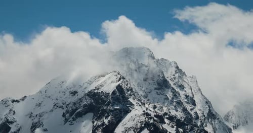 Air Flight Through Mountain Clouds Over Beautiful Snowcapped Peaks of Mountains and Glaciers