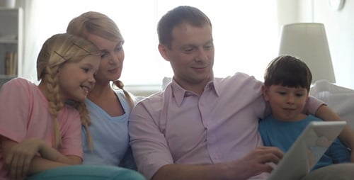 Happy Family Looking at Tablet on Couch Indoors