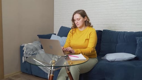 Woman Working on Laptop on Couch at Home
