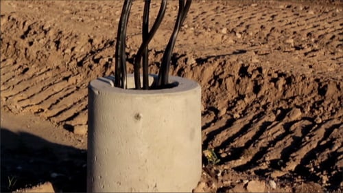 Black Wires Sticking out of Concrete Cylinder in Dirt