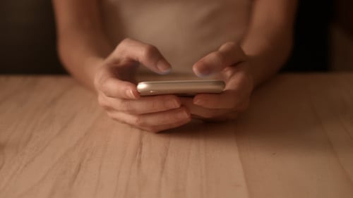 Adult Using Smartphone on Table Indoors
