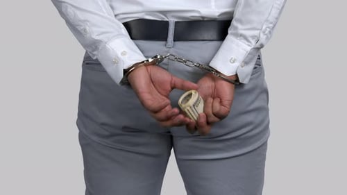 Handcuffed Person Holding Money Behind Their Back