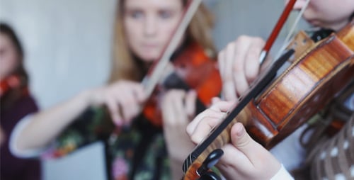 Musicians Practicing Violins in Indoor Setting