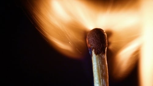 Matchstick Igniting and Burning Against Dark Background