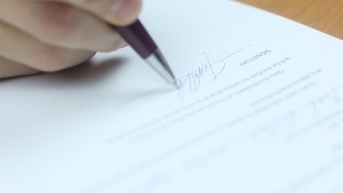 Signing Contract Document with Blue Pen Close Up