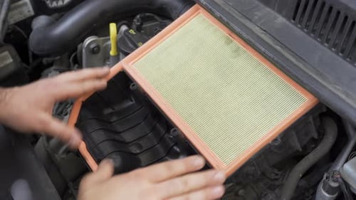 Kaukasischer Mann setzt neuen Luftfilter im Motorraum des Autos ein
