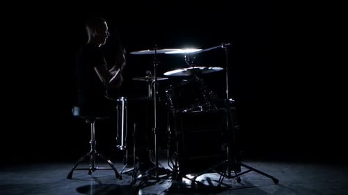 Schlagzeuger spielt energiegeladene Musik auf der Trommel. Schwarzer Hintergrund. Seitlicher Blick