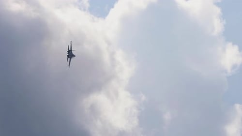 Fighter Jet Flies Through Sky and Clouds