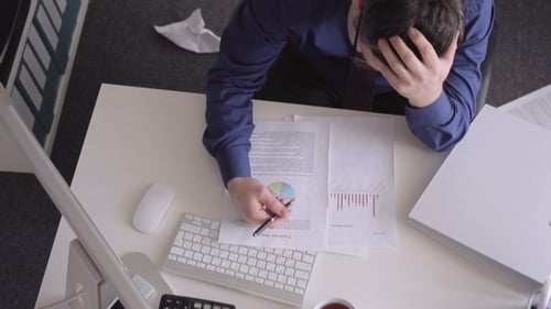 Stressed Adult Man Reviewing Documents in Office