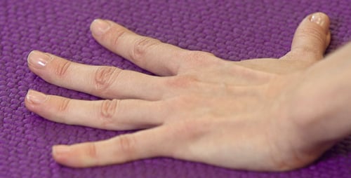 Hand Appearing on Textured Purple Surface