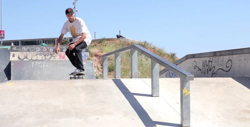 Skateboarder slides along metal bar in Skate Park
