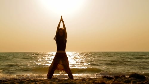 Young Woman Practicing Yoga On Sandy Beach At