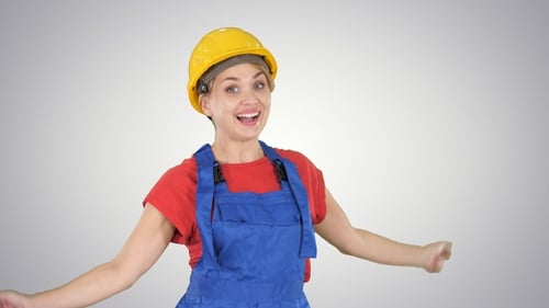 Female construction worker dancing happy on gradient background.
