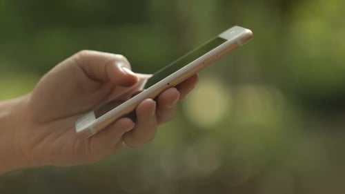 Hand Tapping Smartphone Screen Outdoors