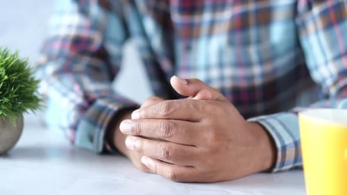 Adult with Hands Clasped at Desk Inside