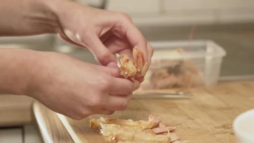 Hands Peeling Shrimp on a Wooden Cutting Board