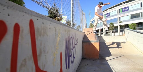 Skateboarder Performs Trick at Urban Skatepark on Sunny Day