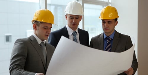 Businessmen Reviewing Blueprints Wearing Hardhats