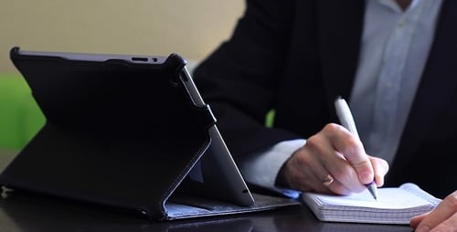 Homme travaillant sur la tablette et écrit dans un cahier