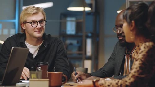 Geschäftsmann spricht bei Night Office Meeting mit multiethnischen Mitarbeitern