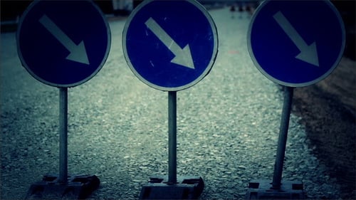 Sinal de estrada para baixo à direita em pé no chão de cascalho