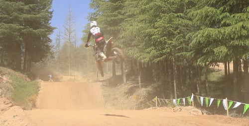 Motocross Racers Jumping on Dirt Track in Forest
