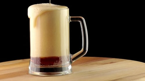 Dunkles Bier wird in einen Becher gegossen