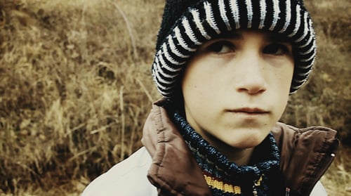 Criança triste com boné de inverno