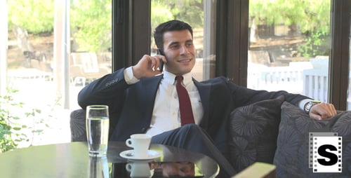 Smiling Businessman Relaxing on Sofa Talking on Phone