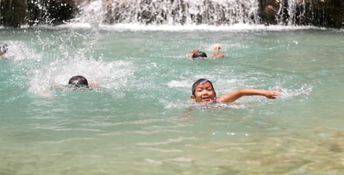 Children Swimming at Tropical Waterfall on Sunny Day