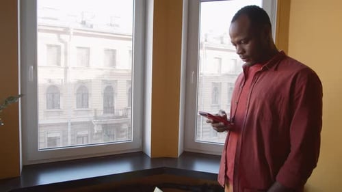 African American Man Using Smartphone in Office Breakout Area