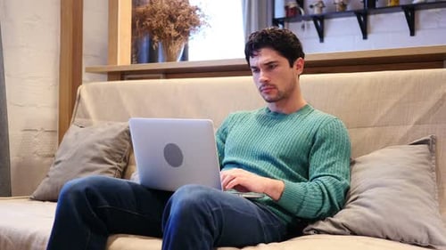 Young Adult on Laptop Typing on Couch