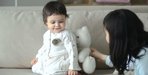 Infant Plays with Toy with Woman on Couch