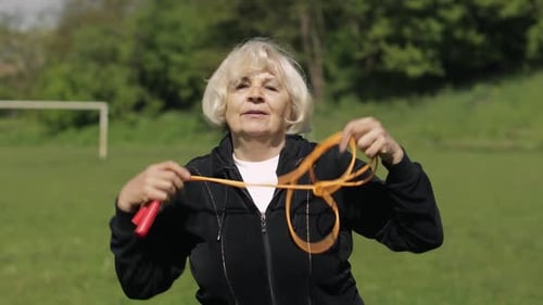 Senior Woman Exercises with Jump Rope Outdoors