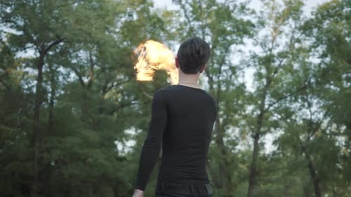 Dark-Haired Man Fire Spinning Performance in Nature