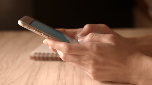 Hands Using a Mobile Phone on Table Indoors